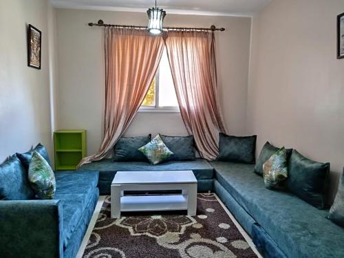 - un salon avec un canapé bleu et une fenêtre dans l'établissement Appartement Ifrane, à Ifrane