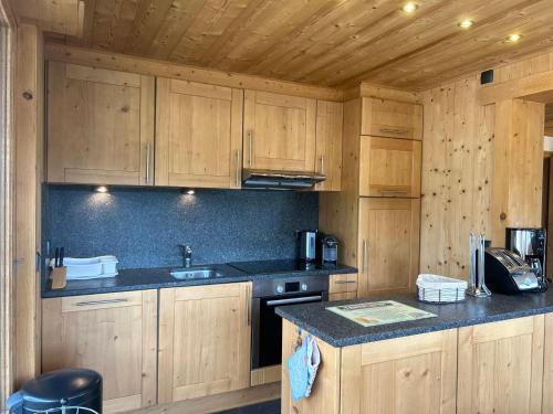 une cuisine avec des armoires en bois et un comptoir noir dans l'établissement Charmant appartement aux Gets - 8 pers, 350m du centre, terrasse et balcon - FR-1-623-90, aux Gets