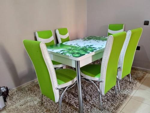 une table et des chaises entourées de chaises vertes dans l'établissement Appartement Ifrane, à Ifrane