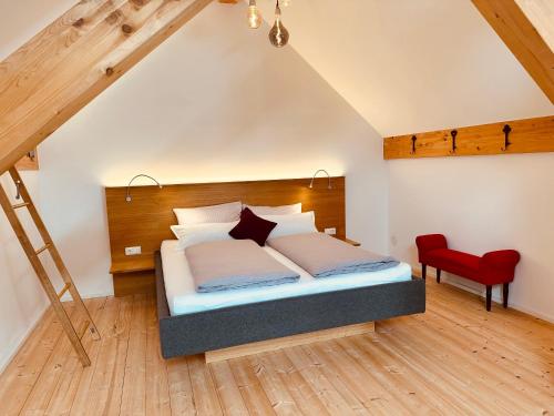 a bedroom with a bed and a red chair at Brunnwirt ESSEN & WOHNEN in Fuschl am See
