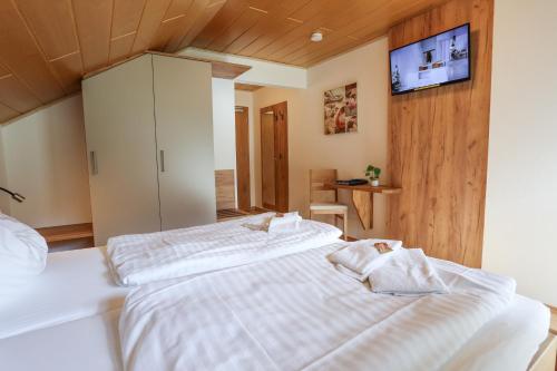 1 dormitorio con 2 camas y TV en la pared en Gasthof Leitner - Der Wirt an der Klamm, en Donnersbach