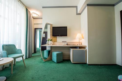 a hotel room with a desk and chairs and a tv at Hotel Malibu in Mamaia