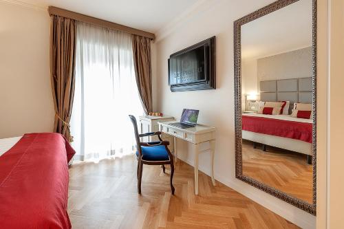 1 dormitorio con espejo, escritorio y cama en Dei Priori Boutique Hotel, en Asís