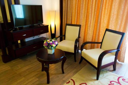 a living room with two chairs and a table with a tv at City Inn Palace Hotel in Ramallah