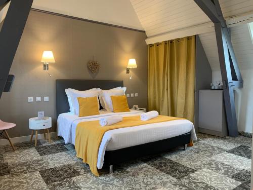 a bedroom with a large bed with yellow pillows at Hotel The Originals Le Manoir de Pierre Levée in Tournon-Saint-Martin