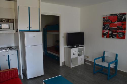 a kitchen with a refrigerator and a tv in a room at Résidence Orion Les Jardins de la Madragde in Cap d'Agde