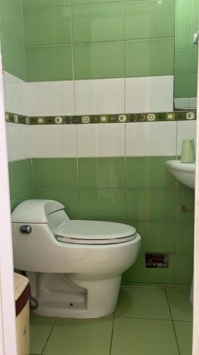 uma casa de banho verde com um WC e um lavatório em Habitación Alborada 2 con baño privado em Lima