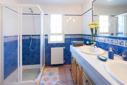 y baño azul y blanco con ducha y lavabo. en Ca na Catalina, en Sant Jordi