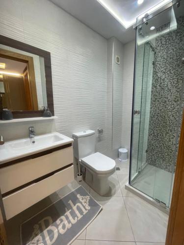 La salle de bains est pourvue de toilettes et d'une douche en verre. dans l'établissement Al amirat martil luxury, à Martil