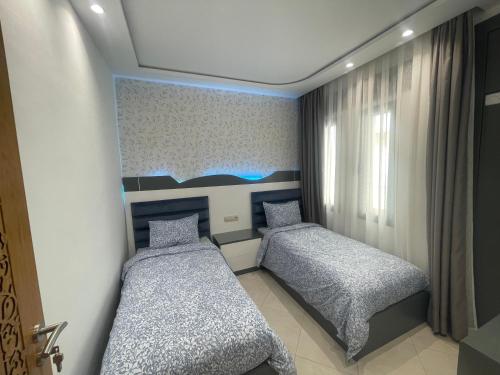 a bedroom with two beds and a painting on the wall at Al amirat martil luxury only family in Martil