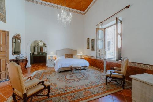 - une chambre avec un lit et deux chaises dans l'établissement Hotel Hacienda La Cieneguita, à San Miguel de Allende