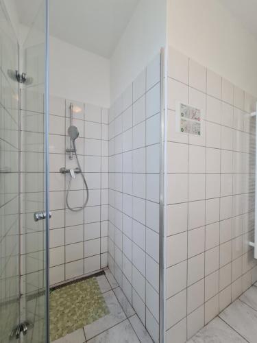 a bathroom with a shower with white tiled walls at NIKA beds in Pardubice