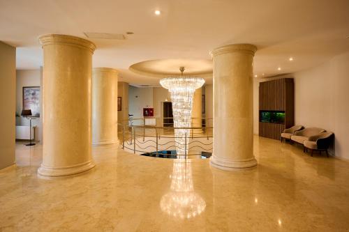 a large lobby with columns and a chandelier at Hotel Malibu in Mamaia
