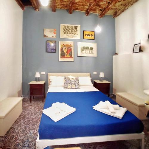 ein Schlafzimmer mit einem blauen Bett, auf dem Handtücher liegen in der Unterkunft PalermHost in Palermo