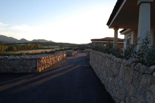 a stone wall next to a road next to a house at Le Ville Le Saline in Palau