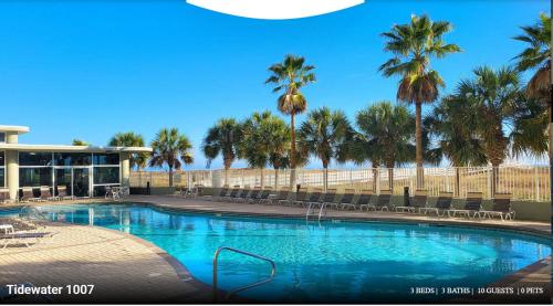 a swimming pool with palm trees and a building at Three-Bedroom Apartment in Orange Beach