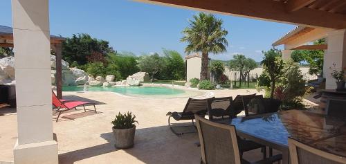 un patio avec une table et des chaises et une piscine dans l'établissement Gîte Atemporelle, à Rochegude