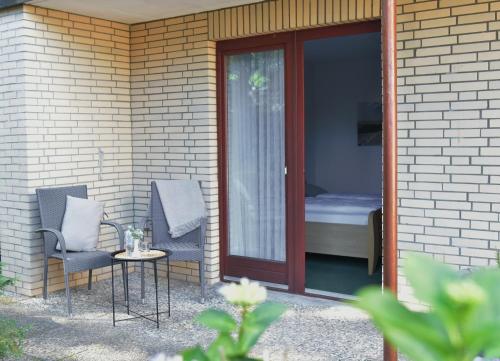 a patio with two chairs and a table next to a door at Pension Haus Bambi in Mölln