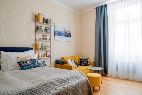 a bedroom with a bed and a chair and a window at Apartment Amélie in Karlovy Vary