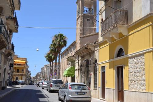 una calle con coches estacionados en un lado de un edificio amarillo en Casa vacanze TRINISULA Sicily home en Scicli