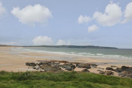 a beach with rocks and the ocean on a cloudy day at Tredarn in Hayle