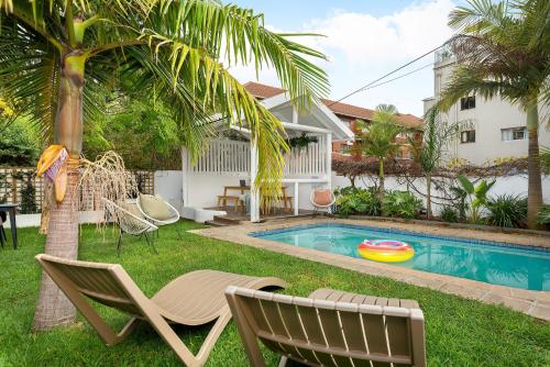 un patio trasero con piscina, sillas y un columpio en Neighbourgood Hill Suites, en Ciudad del Cabo