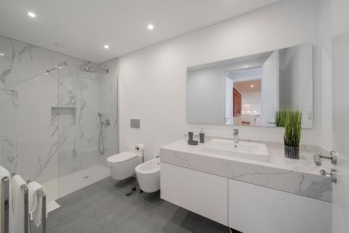 een witte badkamer met een wastafel en een toilet bij OurMadeira - Bayside Apartment in Câmara de Lobos