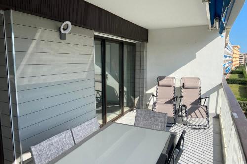 a patio with chairs and a table on a balcony at Le Mistral Appartement Standing vue mer in Le Grau-du-Roi