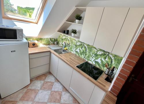 eine kleine Küche mit weißen Schränken und einem Fenster in der Unterkunft Pacek Keco in Alsóörs