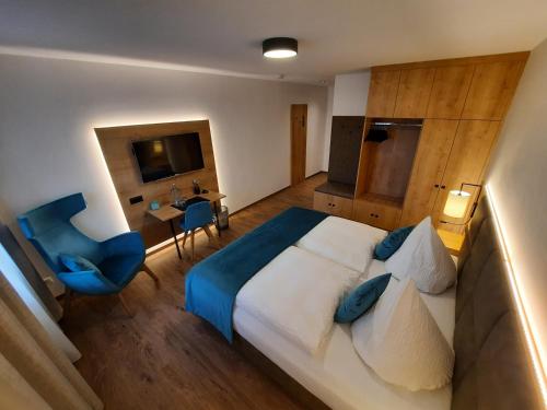 a bedroom with a large bed and a blue chair at Gasthof Krone Ochsenfeld in Ochsenfeld