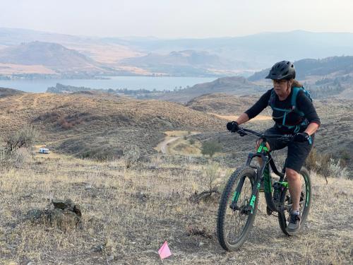 une femme à vélo sur une colline dans l'établissement Sonora Desert Inn, à Osoyoos