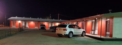 un coche blanco estacionado al lado de un edificio por la noche en Holiday Host Motel & RV Park, en Sonora