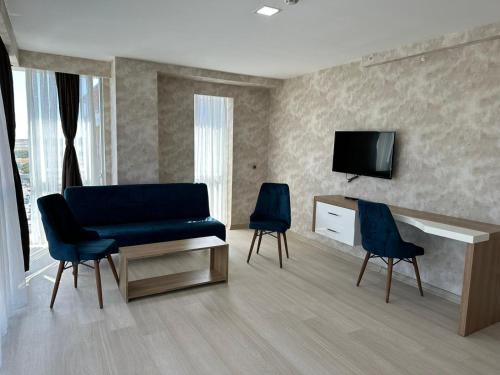 uma sala de estar com um sofá azul e duas cadeiras em GrandPazarcıkOtel 