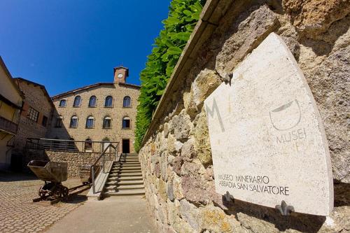 un mur en pierre avec un panneau sur le côté d'un bâtiment dans l'établissement AFFITTACAMERE SANT'ANGELO, à Abbadia San Salvatore