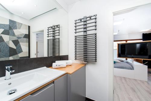 a bathroom with a sink and a tv and a bedroom at Central Apartments by Bed&Bath in Kraków