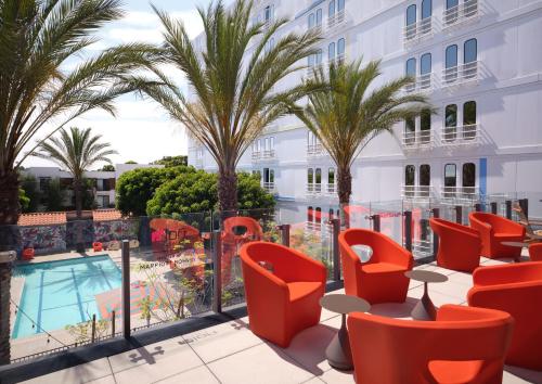 a hotel patio with palm trees and chairs and a pool at Aloft El Segundo - Los Angeles Airport in El Segundo