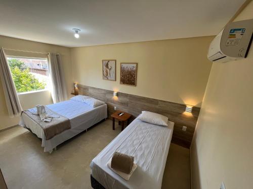 Cette chambre comprend 2 lits et une fenêtre. dans l'établissement Pousada Donna Maraka, à Porto de Galinhas