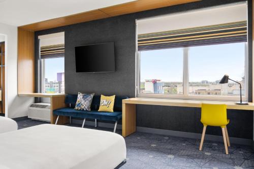 a hotel room with a bed and a desk and windows at Aloft Chicago O'Hare in Rosemont