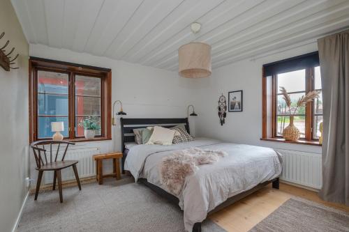 Schlafzimmer mit einem Bett, einem Stuhl und Fenstern in der Unterkunft Brudtallen in Fryksås