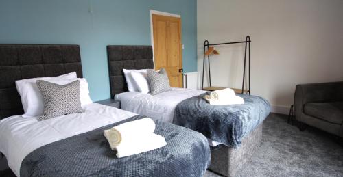 a hotel room with two beds and a couch at Modern 3 Bedroom Home in Northampton by HP Accommodation - Free Parking & Super Fast WiFi in Northampton