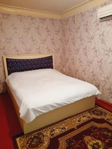 a small bed in a room with pink wallpaper at SAMIR GUEST HOUSE in Ganja