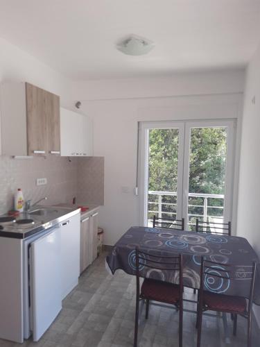 a kitchen with a table and two chairs and a kitchen with a window at Nino Lux Apartments Ulcinj in Ulcinj