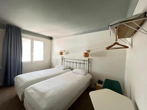 2 bedden in een hotelkamer met een raam bij Grand Hôtel Niort Centre in Niort