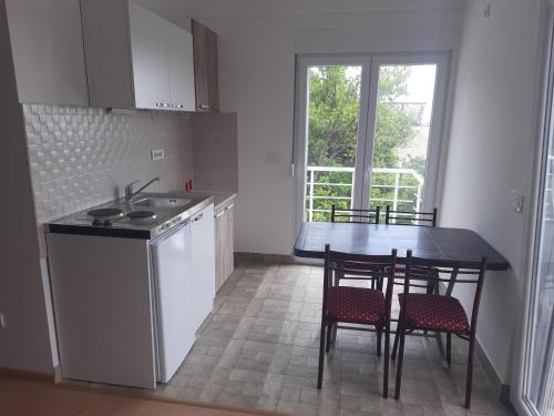 a kitchen with a sink and a table with chairs at Nino Lux Apartments Ulcinj in Ulcinj