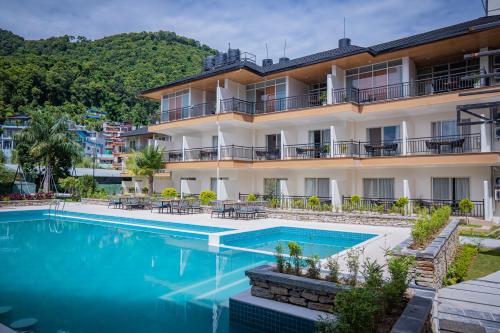 an apartment with a swimming pool in front of a building at Majestic Lake Front Hotel & Suites in Pokhara
