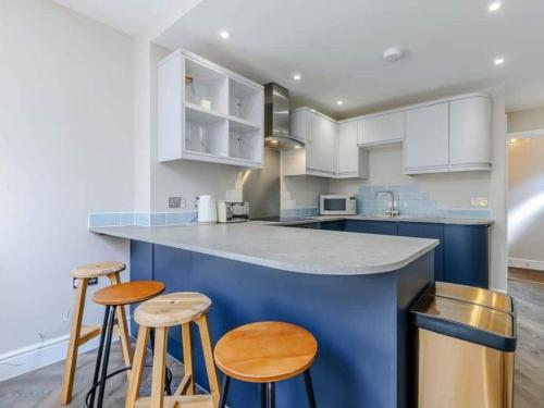 a kitchen with blue and white cabinets and stools at Walpole House sleeps 19-24 in Margate
