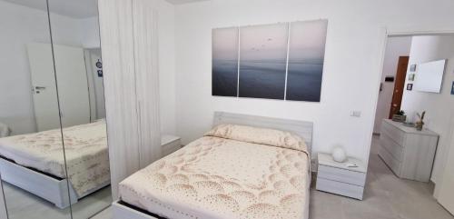 a white bedroom with two beds and a mirror at Casa Chicchina in Senigallia