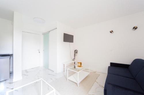 - un salon blanc avec un canapé bleu et une télévision dans l'établissement Studio - Luxury Home, à Bussy-Saint-Georges