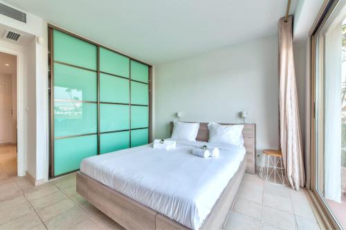 une chambre avec un grand lit avec des draps blancs dans l'établissement La pinede Apartement equiped with air conditioning and a pool!, à Antibes