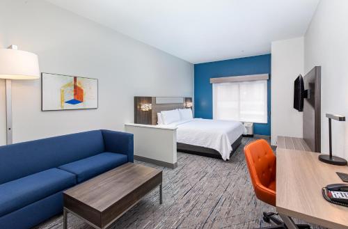 Habitación de hotel con cama y sofá azul en Holiday Inn Express Savannah South I-95 Richmond Hill, an IHG Hotel en Richmond Hill